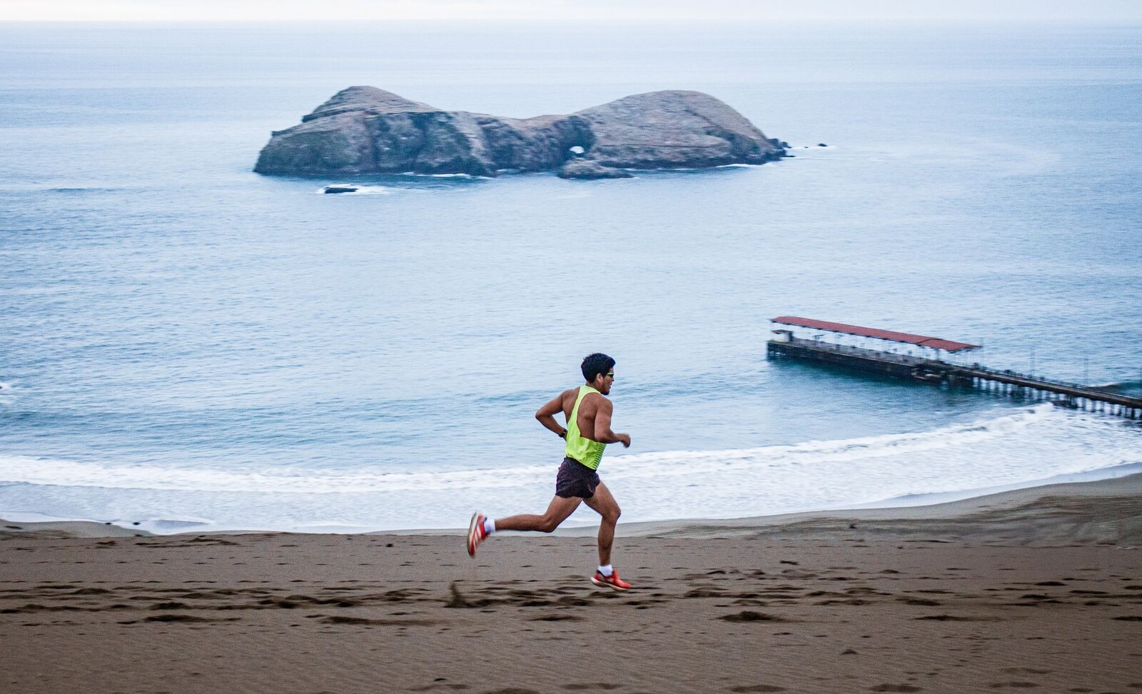 Coureur avançant sur une plage de sable au bord de l’océan
