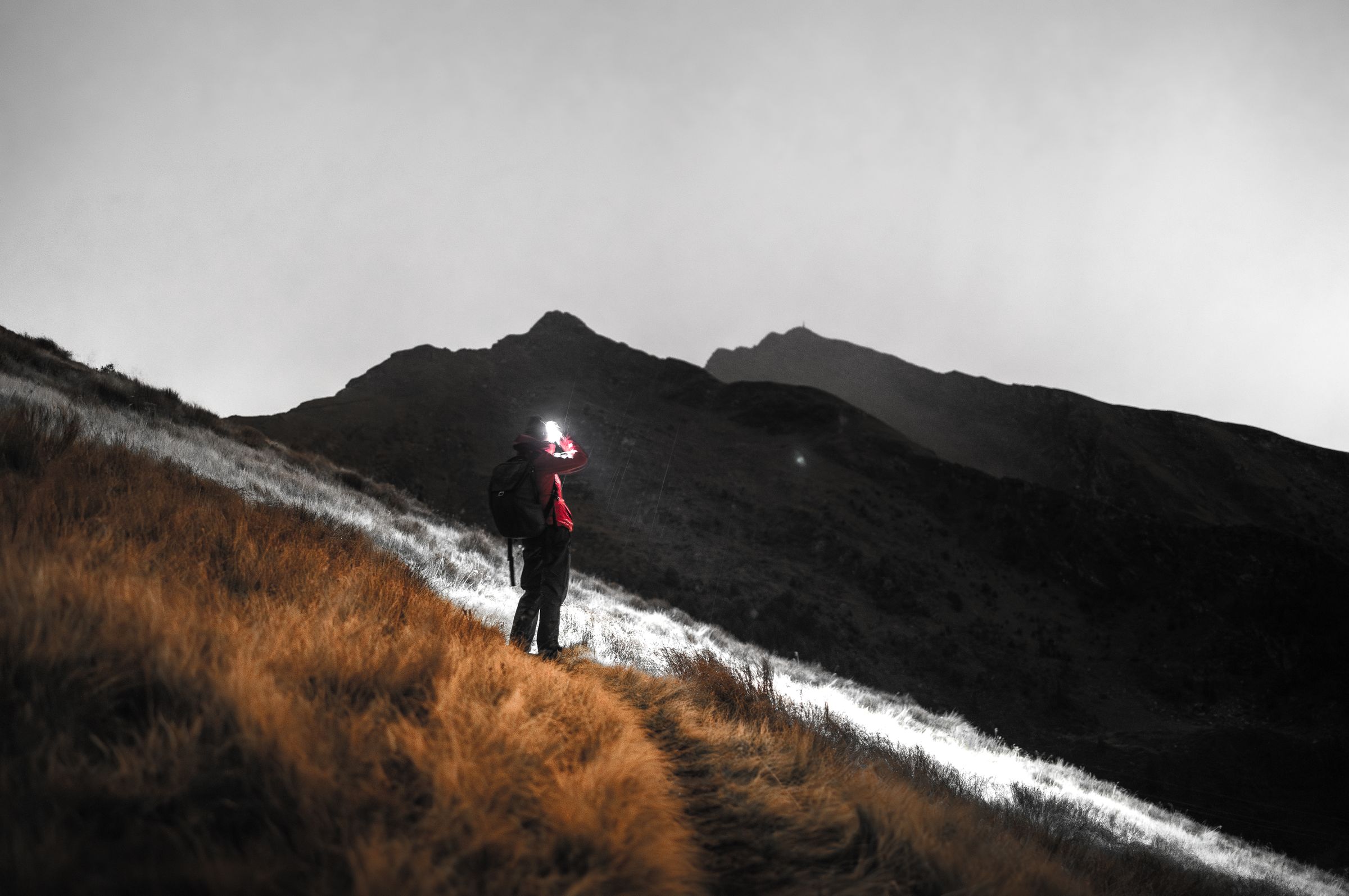 Coureur équipé d’une lampe frontale sur un sentier montagneux nocturne
