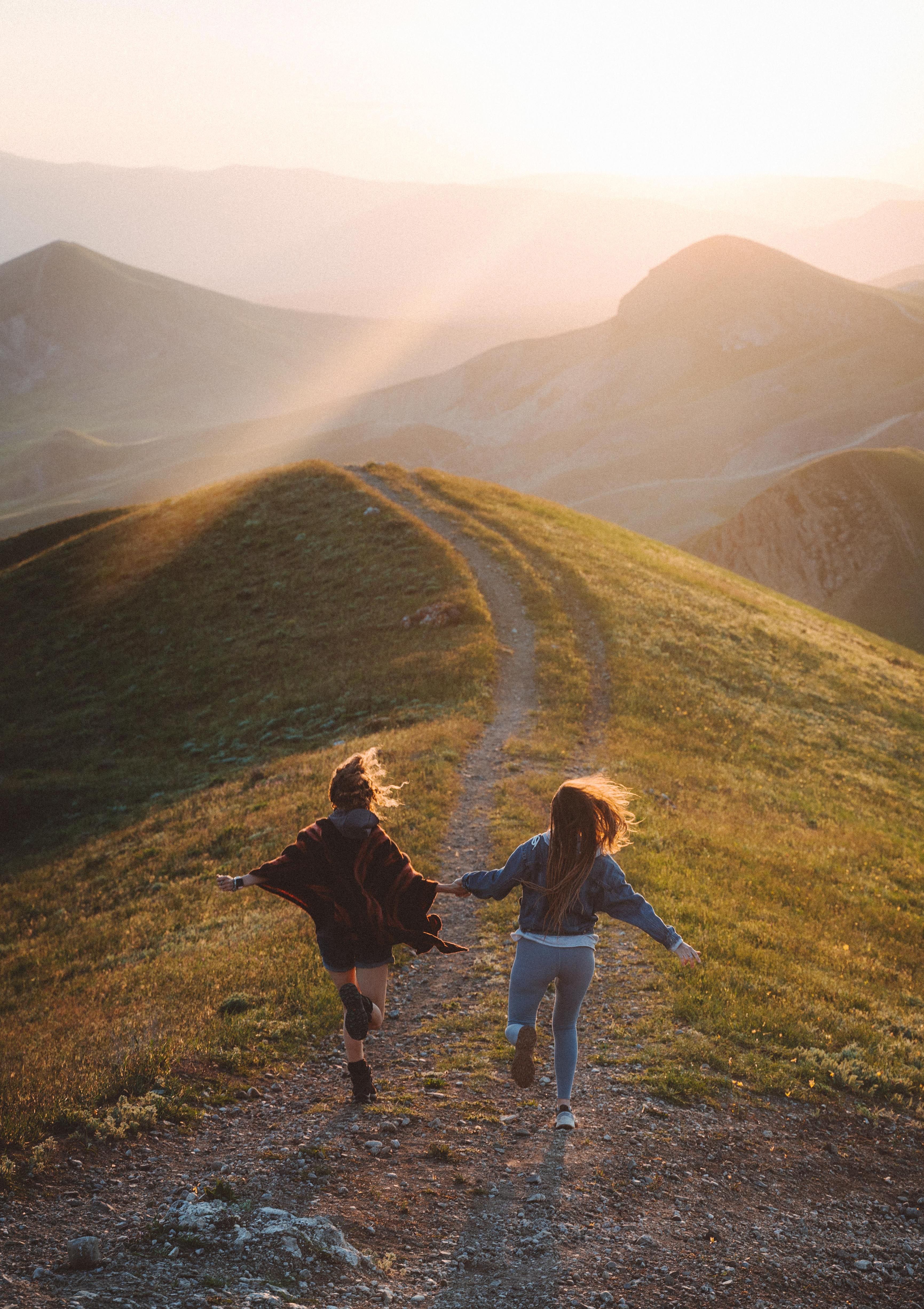Des coureuses progressent sur un sentier de montagne alors que le soleil se couche