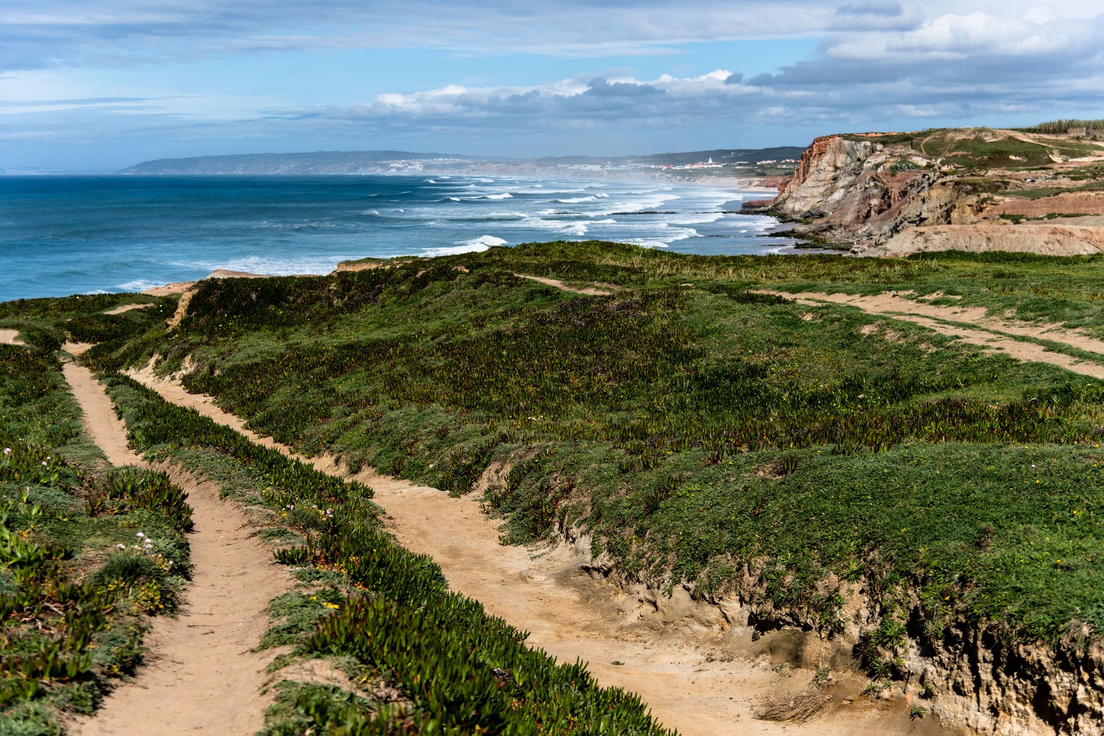 Sentier de crête serpentant entre lande rase et falaises au-dessus de l'océan Atlantique